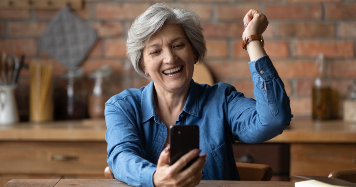 Een gepensioneerde vrouw die enthousiast een flexi job heeft gevonden via een smartphone