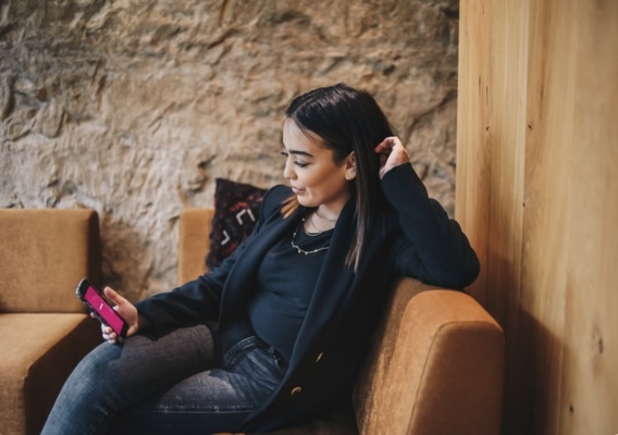 Une femme assise à la recherche d'un job étudiant ou d'un flexi-job via l'application NOWJOBS sur son smartphone.