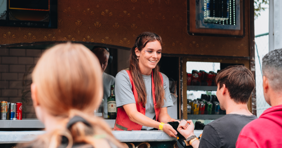 Een goedlachse vrouw die haar studentenjob uitvoert achter de bar van Tomorrowland