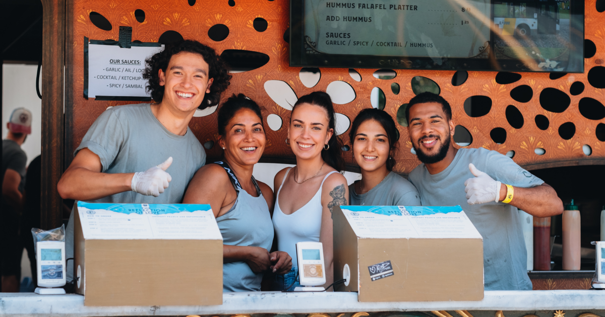 Vijf enthousiastemannen en vrouwen die hun vakantiejob uitvoeren achter de bar op Tomorrowland