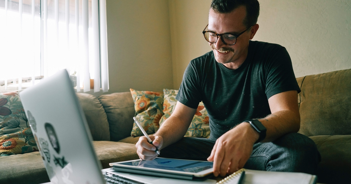 Glimlachende man werkend op zijn laptop en tablet
